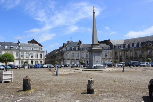 Photographie d'une perspective urbaine de la ville d'Arras montrant un ensemble de bâtiments résidentiels ou patrimoniaux typiques de l'architecture des Hauts-de-France avec des toitures en ardoise, zinc ou cuivre visibles et bien détaillées. La photo doit être prise en lumière naturelle de jour, capturer l'environnement urbain caractéristique d'Arras, sans personne visible, et mettre en évidence la qualité et la diversité des couvertures pour illustrer le savoir-faire en couverture artisanale sur ce territoire.