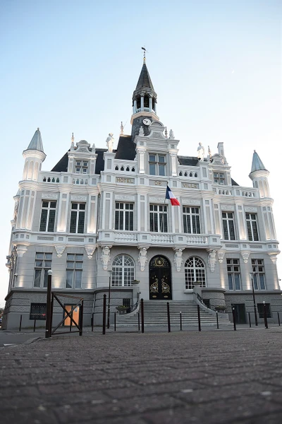 Photographie d'une toiture en ardoise d'une maison traditionnelle dans un contexte de bâtiment ancien ou patrimonial des Hauts-de-France, prise en vue générale montrant la qualité de la couverture et les finitions. L'image doit présenter clairement les matériaux de couverture noble (ardoise) et la précision du travail artisanal, sans personne visible, dans une lumière naturelle en conditions de jour.