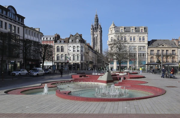 Photographie d'une rue typique de Douai avec des bâtiments résidentiels ou commerciaux du nord de la France (architecture traditionnelle des Hauts-de-France), montrant clairement une ou plusieurs toitures en ardoise ou en matériaux nobles (zinc, cuivre) depuis une perspective qui situe géographiquement la localité. La photo doit être prise en lumière naturelle de jour, sans personne visible, et mettre en évidence la qualité des couvertures et finitions pour démontrer la pertinence de l'intervention d'un couvreur artisanal sur ce territoire.